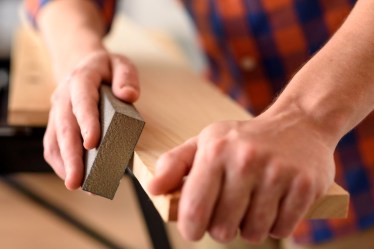 iStock-1303154686-how-to-sand-wood-hands-using-sanding-block